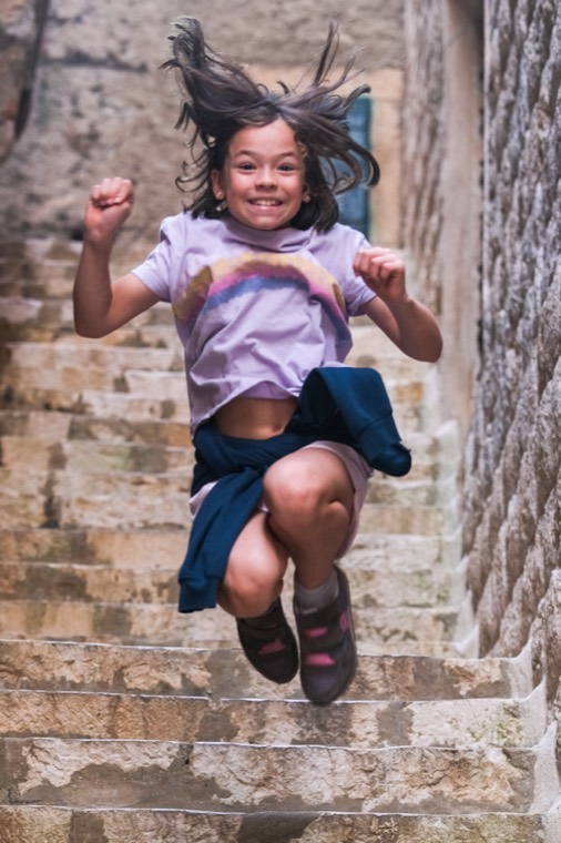 girl jumping on stone stairs